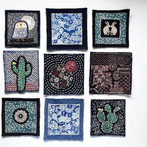 May include: A collection of nine square fabric patches featuring various embroidered designs including an owl, a cactus, rabbits, floral patterns, and a dragonfly. Each patch is crafted with different textile textures and colors.