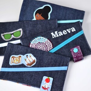 Peut inclure: Quatre étuis à crayons en jean avec des motifs brodés différents. Les étuis ont des accents bleus et turquoise. Un étui représente une fille à la peau brune, un autre une paire de lunettes de soleil vertes, un autre un bateau et une carte, et le dernier porte le nom "Maeva" brodé.