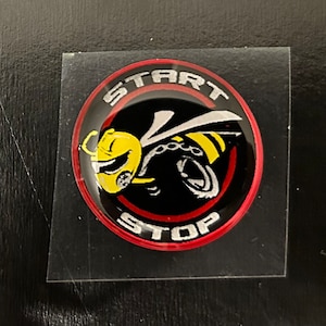 May include: A black and red round sticker with a yellow and black bee illustration. The sticker says "START" and "STOP" in a white circle.