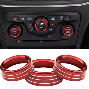 May include: Three red aluminum rings with silver stripes for car interior trim. The rings are designed to fit around the knobs of a car's climate control and audio system.