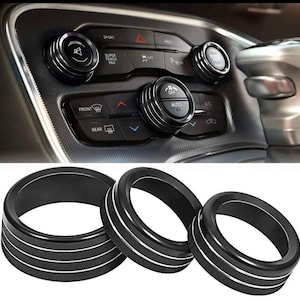 May include: Three black car interior trim rings with silver accents. The rings are designed to fit around the knobs of a car's climate control system.