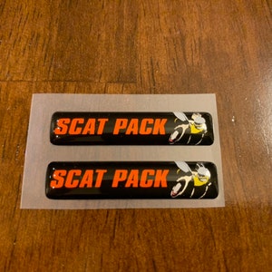 May include: Two black and orange "SCAT PACK" emblems with a yellow and black bee graphic.