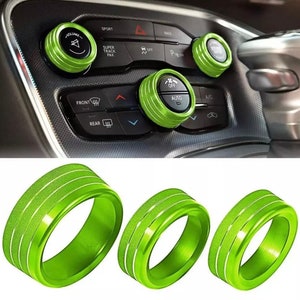 May include: Three green aluminum rings with a textured surface. The rings are designed to fit around the knobs of a car's dashboard.