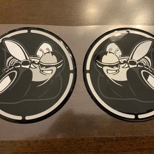 May include: Two black and white round stickers with a cartoon bee wearing sunglasses and holding a tire. The bee is in a circle with a white outline.