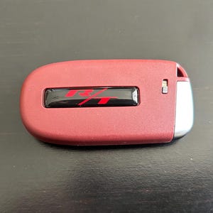 May include: A red car key fob with a black and red "R/T" logo.