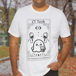 May include: A white t-shirt with a black and white graphic of a ghost holding a cup with a plus sign. The graphic is in the style of a tarot card and says "CT Tech The Contrast Coordinator".