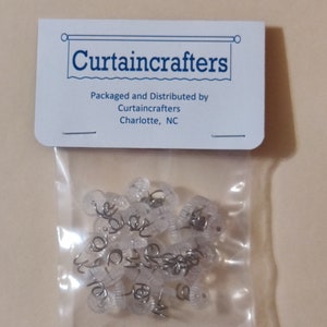 May include: A clear plastic bag containing several clear curtain clips with metal spiral springs. The bag has a white header with the text "Curtaincrafters". The header also includes the text "Packaged and Distributed by Curtaincrafters Charlotte, NC".