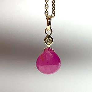 May include: A delicate gold chain necklace with a pink gemstone pendant and a small diamond accent.