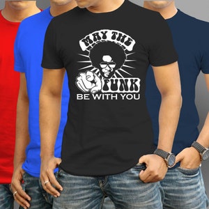 Puede incluir: Una camiseta negra con un gráfico blanco de un hombre con afro que lleva gafas de sol y apunta al espectador. El texto "May the Funk Be With You" está impreso debajo del gráfico.