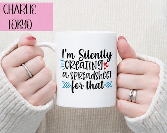 May include: White ceramic mug with a blue and red graphic that says "I'm silently creating a spreadsheet for that".