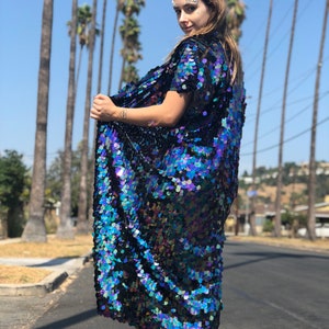 Puede incluir: Un kimono largo, azul y negro iridiscente con lentejuelas, de manga corta. El kimono est&aacute; hecho de peque&ntilde;as lentejuelas superpuestas que crean un efecto brillante.