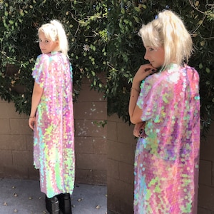 May include: A long, iridescent sequin kimono in shades of pink, purple, and green. The short-sleeved garment is knee-length and appears to be made of a sheer fabric. The sequins catch the light, creating a shimmering effect.