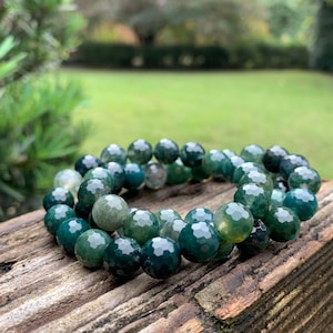 May include: A green agate gemstone bracelet with faceted beads. The bracelet is made of natural stones and has a dark green and light green colour.