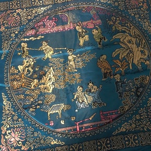 May include: A round blue and gold tapestry with a circular design featuring children playing in a garden setting. The tapestry is surrounded by a gold border with floral motifs.