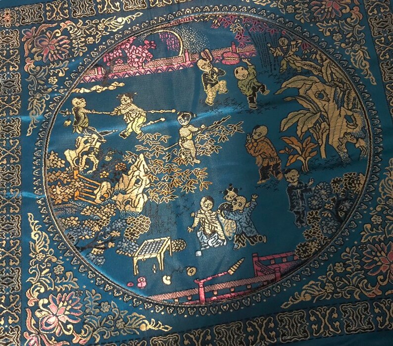 May include: A round blue and gold tapestry with a circular design featuring children playing in a garden setting. The tapestry is surrounded by a gold border with floral motifs.