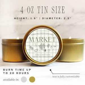 May include: Gold-colored tin candle with a label that reads "THEY'RE FRESH OFF THE MARKET." The candle is 1.8 inches high and 2.5 inches in diameter. The label features a green and white checkered pattern with fruit illustrations. The text "ANNA & MATTHEW THANK YOU FOR COMING" is also on the label.
