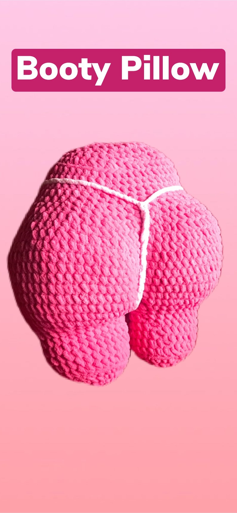 Peut inclure: Un coussin rose en crochet en forme de fesses, avec un d&eacute;tail de ficelle blanche. Le texte "Booty Pillow" est affich&eacute; dans un rectangle rose en haut de l'image. Le fond est rose uni.