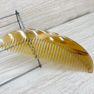 May include: A brown tortoise shell comb with a wide tooth design.