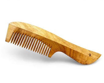 Può includere: Un pettine in legno marrone chiaro con venature naturali, caratterizzato da un manico curvo e una serie di denti distanziati uniformemente. Il pettine ha una finitura liscia e lucida e un piccolo logo circolare scuro sull'estremità del manico.