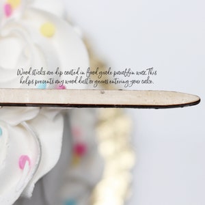Peut inclure: Un b&acirc;tonnet en bois de couleur claire avec une finition lisse enduite de cire, positionn&eacute; horizontalement. Le texte sur l'image indique : Wood sticks are dip coated in food grade paraffin wax. This helps prevents any wood dust or germs entering your cake.