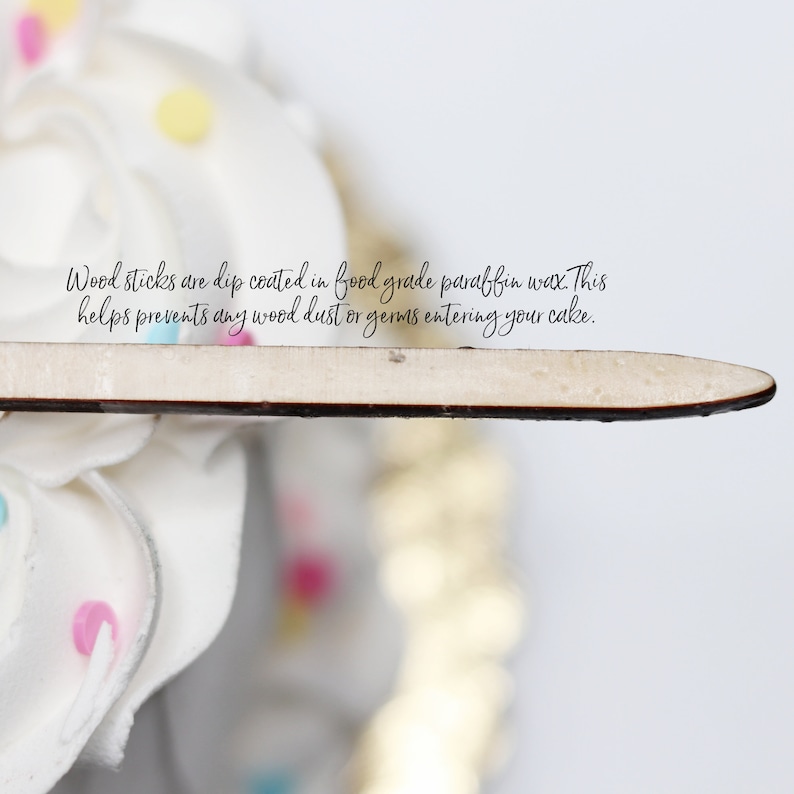 Peut inclure: Un b&acirc;tonnet en bois de couleur claire avec une finition lisse enduite de cire, positionn&eacute; horizontalement. Le texte sur l'image indique : Wood sticks are dip coated in food grade paraffin wax. This helps prevents any wood dust or germs entering your cake.