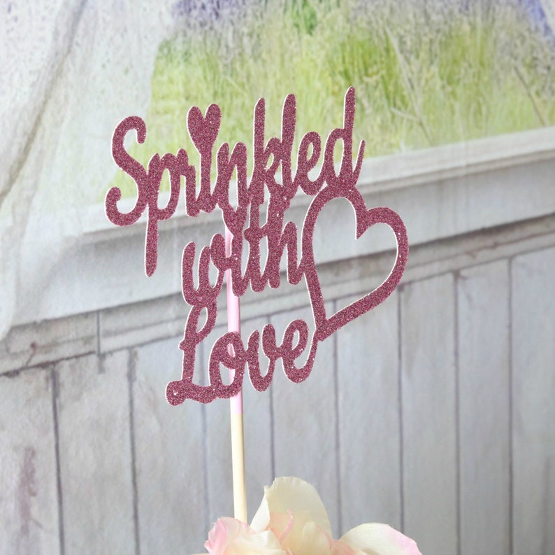 May include: Pink glitter cake topper with the text "Sprinkled with Love" and a heart.
