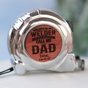 May include: A silver tape measure with a wooden insert that reads "Some people call me a Welder. The most important call me Dad. Love, Cam & Cal."