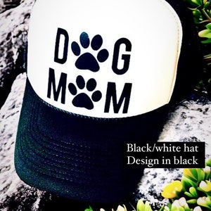 May include: Black and white trucker hat with a black paw print design that says "Dog Mom".