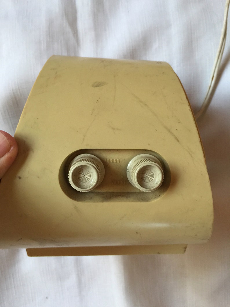 May include: A beige vintage radio with two round knobs labeled "Tuning" and "Volume".