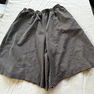 Op de afbeelding: Zwart-witte gingham shorts met een brede tailleband en een ontspannen pasvorm.
