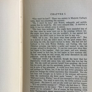 May include: A vintage book with a cream-colored cover and black text. The title of the book is "Chapter I." The text on the page discusses a woman named Marjorie Carling and her relationship with a man named Walter.