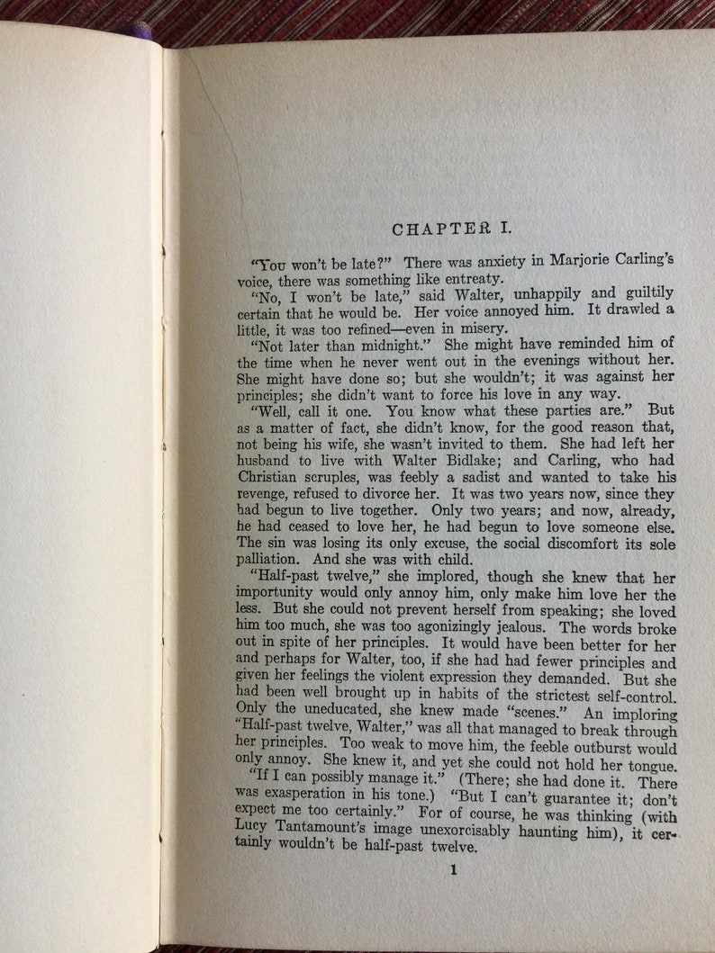 May include: A vintage book with a cream-colored cover and black text. The title of the book is "Chapter I." The text on the page discusses a woman named Marjorie Carling and her relationship with a man named Walter.