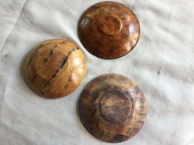 May include: Three wooden bowls with different patterns and colors. The bowls are brown, tan, and purple with a speckled pattern.