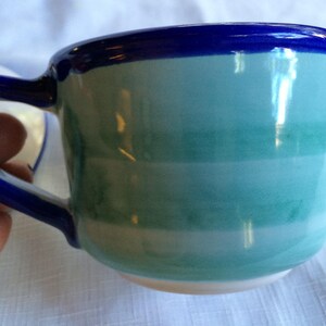 May include: A blue and green striped ceramic teacup with a blue rim.