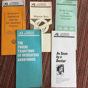 May include: Five pamphlets with blue and white text on a white background. The pamphlets are about Overeaters Anonymous and feature titles like "The Twelve Traditions of Overeaters Anonymous", "Welcome Back", "To the Family of the Compulsive Overeater", "As Seen by a Doctor", and "Compulsive Overeating and the OA Recovery Program".