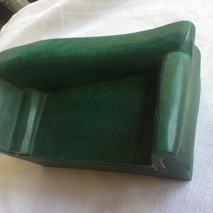 May include: A small, green, wooden sofa with a simple design. The sofa is made of wood and has a smooth, painted finish.