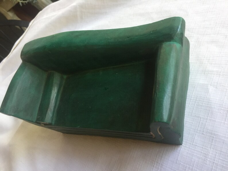 May include: A small, green, wooden sofa with a simple design. The sofa is made of wood and has a smooth, painted finish.