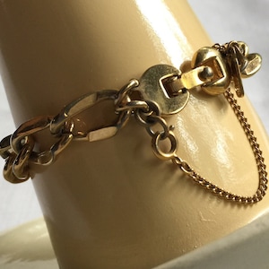 Puede incluir: Un brazalete de cadena en tono dorado con un diseño de eslabones gruesos y un cierre de langosta. El brazalete tiene una extensión de cadena delicada.