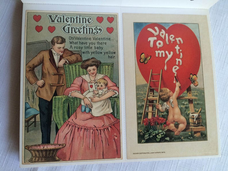 K&ouml;nnte beinhalten: Zwei Vintage-Valentinstagskarten. Die linke Karte zeigt eine Familienszene mit dem Text "Valentine Greetings". Die rechte Karte zeigt einen Engel, der ein Herz mit den Worten "To my Valentine" malt.