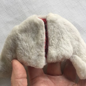 May include: A white faux fur jacket with a red and white patterned lining. The jacket is open and the lining is visible.