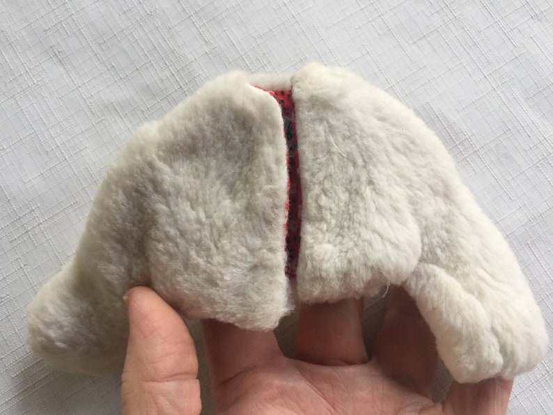 May include: A white faux fur jacket with a red and white patterned lining. The jacket is open and the lining is visible.