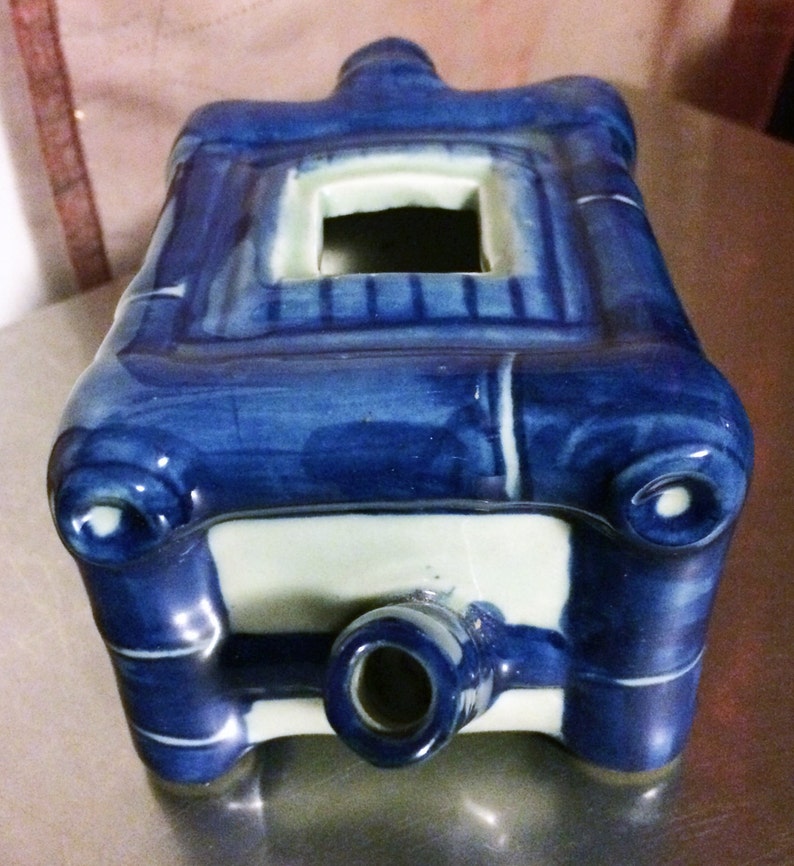 Peut inclure: Br&ucirc;le-encens en c&eacute;ramique bleu et blanc de forme rectangulaire avec une petite ouverture sur le dessus. Le br&ucirc;leur est d&eacute;cor&eacute; de motifs de tiges de bambou et d'un bec verseur sur le dessous.