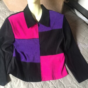 May include: A black, pink, and purple color block jacket with a zipper closure.