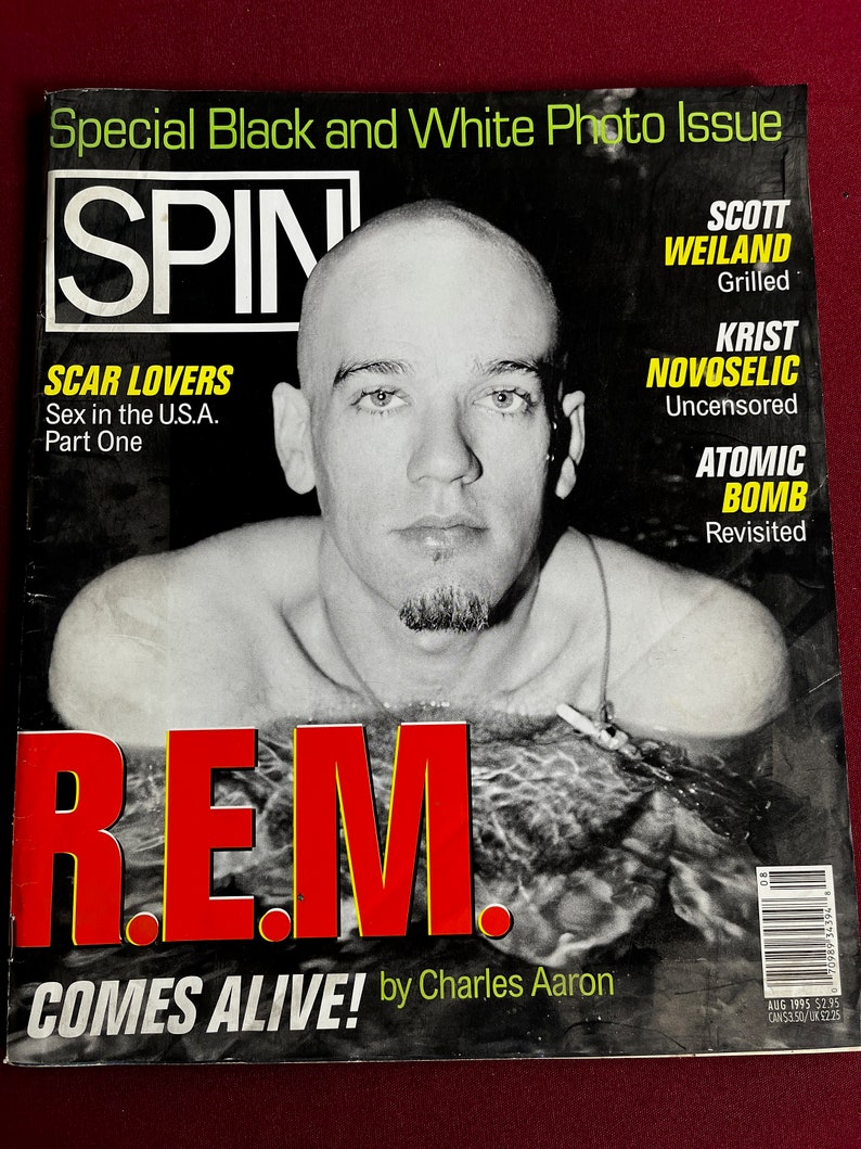 May include: A black and white photo of a man in a swimming pool. The magazine cover is for SPIN magazine and features the band R.E.M. with the text "COMES ALIVE! by Charles Aaron".