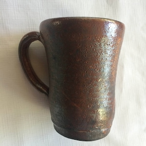 May include: A brown ceramic mug with a textured surface and a rounded handle.