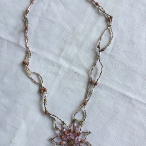 Pode incluir: Um colar de contas marrons e rosa com um pingente em forma de flor.