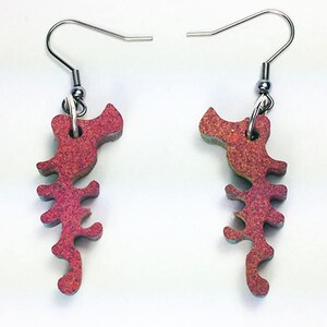 May include: A pair of earrings featuring a red and orange seahorse design. The seahorses are made of a textured material and have a slightly iridescent finish.