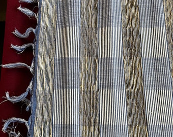 May include: A blue and gold woven placemat with fringe on the edges.