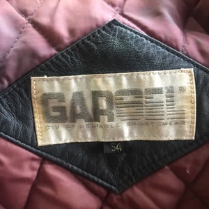 Pu&ograve; includere: Una toppa in pelle nera con un'etichetta bianca che recita "GARCEY DIV. OF RELIABLE SPORTSWEAR" e un'etichetta di taglia che indica "54".