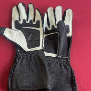 Puede incluir: Un par de guantes de carreras en blanco y negro. Los guantes tienen palmas y dedos de cuero blanco, con tela negra en el dorso de la mano y la mu&ntilde;eca. Dise&ntilde;ados para agarre y protecci&oacute;n.